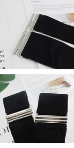 Detail view of black elastic waist belt featuring a silver interlocking metal buckle closure
