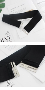 Detail of black elastic waist belt with silver metal buckle and textured fabric strap
