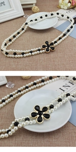 Dettaglio dell'elegante catena in vita a doppio filo di perle con chiusura a fiore nero