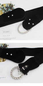 Detail of floral rhinestone buckle and metal leaf pendant on black elastic wide belt