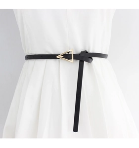 Detailed close-up of a slim black leather belt with a gold triangle buckle on a white dress