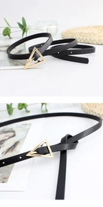 Close-up of thin black leather belt with golden triangle buckle and refined texture