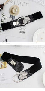 Detailed view of swan buckle with white rhinestones on black elastic belt for women