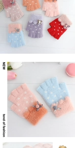 Detailed close-up of fluffy kids' half-finger gloves with bows and polka dots on wood