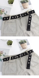 Détail de la ceinture en toile noire à œillets avec boucles cœur et carrée sur denim