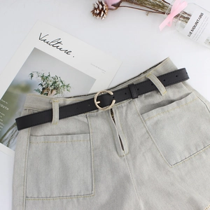 Cintura sottile da donna in pelle nera con fibbia dorata su jeans chiari