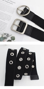 Détail d'une ceinture en toile noire avec œillets métalliques et boucle mate