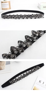 Close-up of black elastic belt featuring sparkling grey crystal rhinestone details