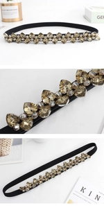Detail shot of black elastic waist belt featuring amber crystal inlay and heart rhinestones