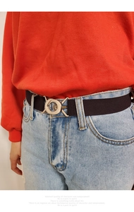 Close-up of black elastic waist belt with round hollow metal buckle on denim jeans