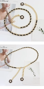Detail of gold metal waist chain with black leather and pearl camellia flower pendants