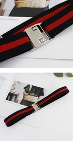 Detail view of red and black striped elastic belt with silver interlocking buckle