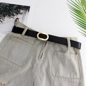Minimalist black leather belt with golden oval buckle styled on casual denim shorts
