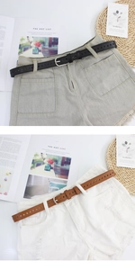 Dettaglio di cinture sottili in pelle con stelle su pantaloncini di jeans grigi e bianchi
