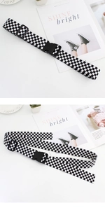 Détail d'une ceinture en toile à damier réglable avec boucle en plastique noir robuste