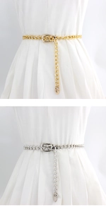 Detail of gold and silver thin metal chain belts with heart pendants on a white dress