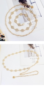 Détail de la chaîne de taille en métal doré avec fleurs en strass et pendentif rose