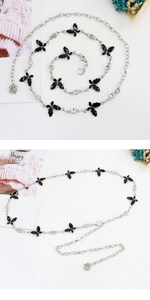 Detail of silver chain belt with black butterfly charms and rose pendant on white background