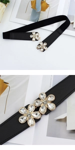 Close-up of black elastic waist belt featuring a gold floral buckle with sparkling rhinestones
