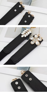 Detail of black elastic belt set featuring crystal flower buckles and snap closure buttons
