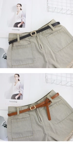 Detail of high waist denim shorts with frayed edges and thin gold buckle leather belt