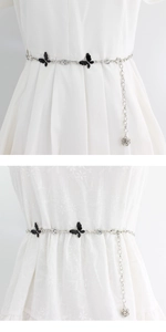 Detail of silver bow waist chain with black enamel and rose pendant on white dress