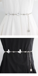 Detail view of silver metal waist chain with white butterfly and rose pendant on dress