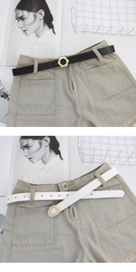 Détail d'une ceinture pour femme à boucle fleurie dorée sur un short en jean beige effiloché