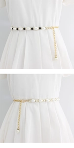 Detail der Taillenkette mit schwarz-weißen Perlen und Goldgliedern auf weißem Kleid
