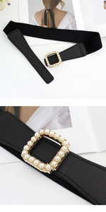 Détail d'une boucle carrée dorée avec perles sur une ceinture élastique noire