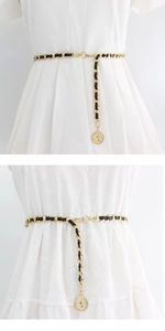 Detail of elegant gold metal chain woven with black leather and round pendant for dresses