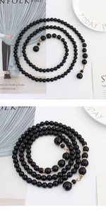 Détail d'une ceinture en perles noires avec des anneaux dorés sertis de strass et des pendentifs