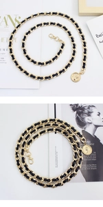 Detail of gold metal and black leather woven waist chain with a round coin pendant charm