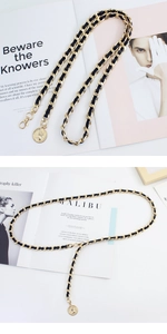 Detail of gold metal chain woven with black leather featuring a vintage coin pendant