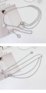 Close-up of layered silver chain belt with sun medallion charms on a white background