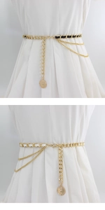 Detail of layered gold metal waist chain with leather weaving and vintage coin pendant