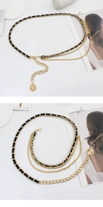 Detail of gold metal chain belt with woven black leather and a hanging coin charm