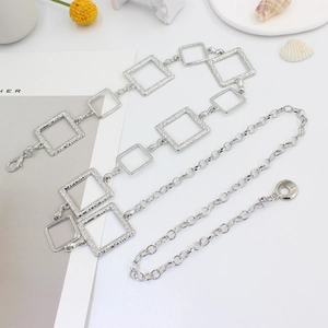 Women's silver square link metal chain belt on a minimalist white styling background