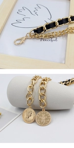 Detail view of gold chain belt with black PU leather weave and vintage coin pendants