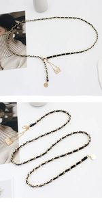 Detail view of a gold chain belt with black leather strap, lobster clasp and square pendant