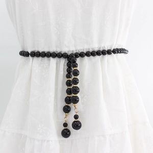 Chaîne de taille élégante en perles noires avec accents dorés sur robe blanche