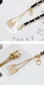 Detail of gold metal and black leather woven waist chain with a mini quilted bag charm