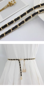 Detail of woven gold chain belt with black leather and miniature purse charms