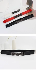 Detail of vintage embossed rose metal buckle on a slim elastic waist belt for women
