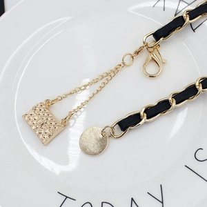 Elegant gold metal chain belt with black leather weave and quilted mini bag charm