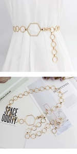 Close-up of gold hexagonal metal waist chain with lobster clasp on white dress