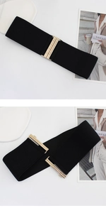 Detail of black elastic waist belt featuring a polished gold metallic interlocking buckle