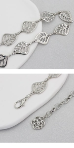 Close-up of silver metal leaf links and floral charm detail on a stylish waist chain belt