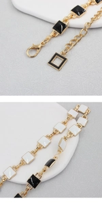 Detailed macro view of gold metal chain with black and white enamel squares and clasp