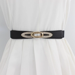 Cintura elastica con fibbia dorata con strass su abito bianco per un look slim fit
